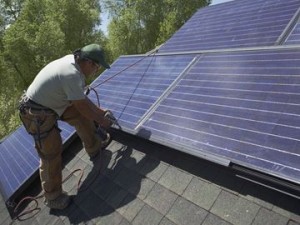 Construction worker installing solar panel on roof